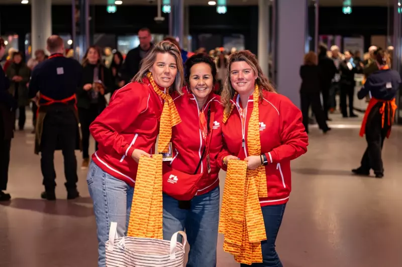 Drie Postcode Loteri-collega's delen sjaaltjes uit aan deelnemers tijdens het André Rieu event